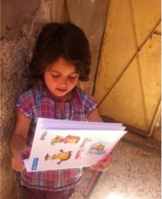 A young girl receives hygiene promotion material in a host community. Source: UNICEF JORDAN (2013).